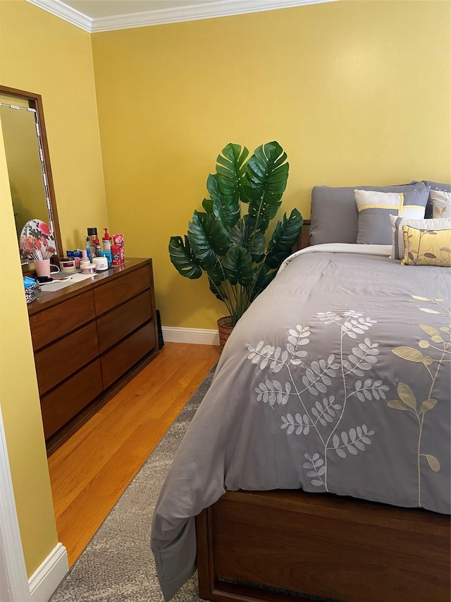 bedroom with wood finished floors, ornamental molding, and baseboards