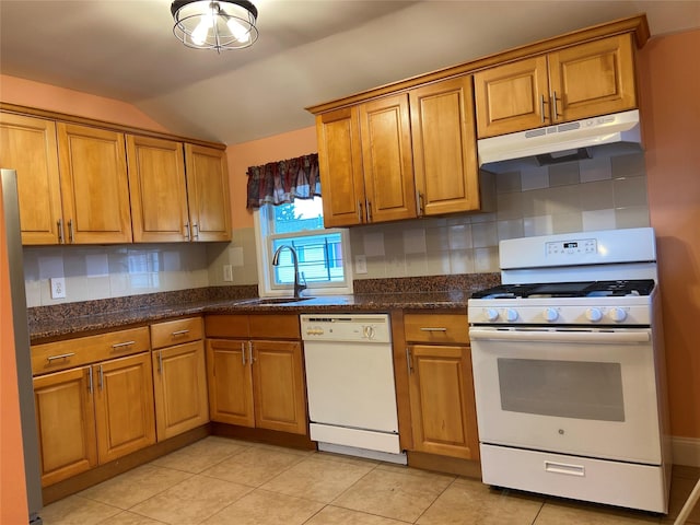 kitchen featuring a sink, brown cabinets, under cabinet range hood, white appliances, and lofted ceiling