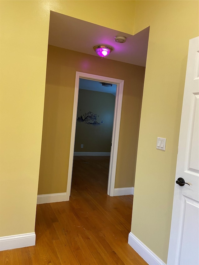 hall with baseboards and wood finished floors