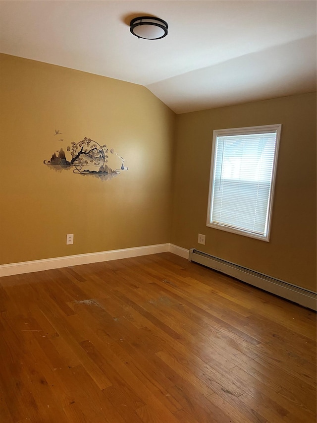 spare room featuring baseboards, a baseboard heating unit, lofted ceiling, and wood-type flooring