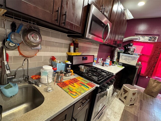 33-40 101st St, Corona, NY 11368 - kitchen with light stone counters, a sink, appliances with stainless steel finishes, dark brown cabinetry, and backsplash