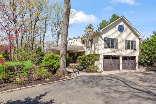 split level home with driveway, a chimney, and a garage