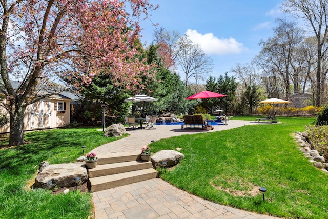 view of property's community featuring a patio area, an outbuilding, a yard, a storage shed, and a pool
