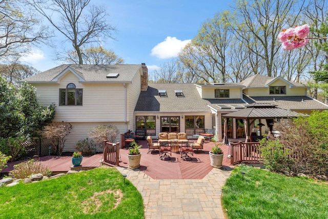 rear view of property with a wooden deck, a shingled roof, outdoor lounge area, a lawn, and a chimney
