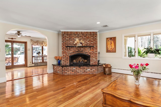 living room with a baseboard radiator, visible vents, ornamental molding, and a brick fireplace