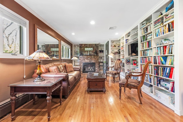living area featuring a fireplace, a wealth of natural light, visible vents, and wood-type flooring