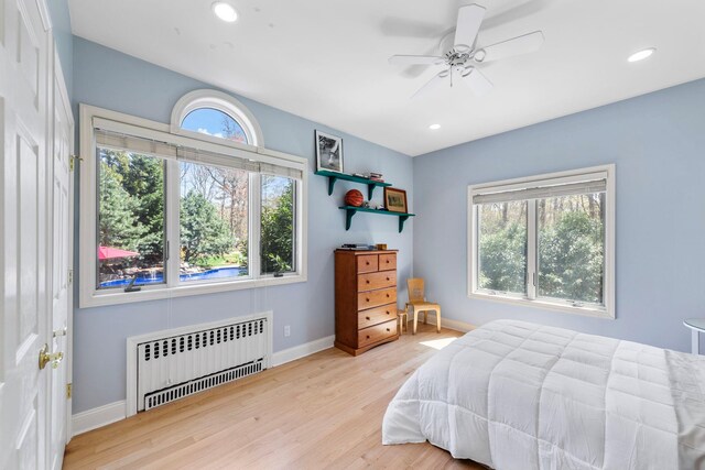 bedroom featuring recessed lighting, radiator heating unit, wood finished floors, and baseboards
