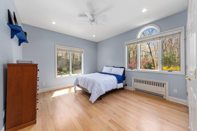 bedroom featuring multiple windows, light wood-style floors, and radiator