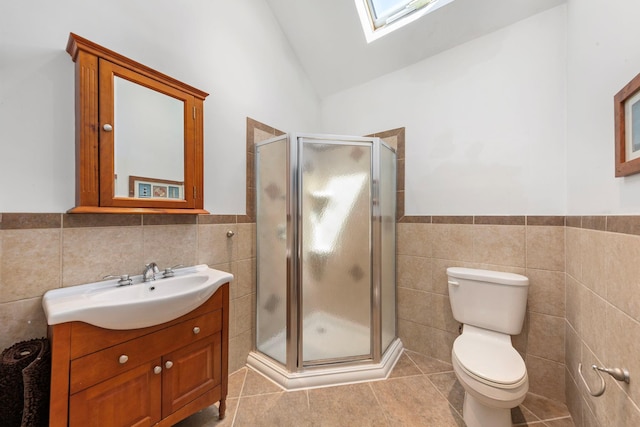 bathroom with tile walls, a shower stall, vanity, tile patterned flooring, and wainscoting