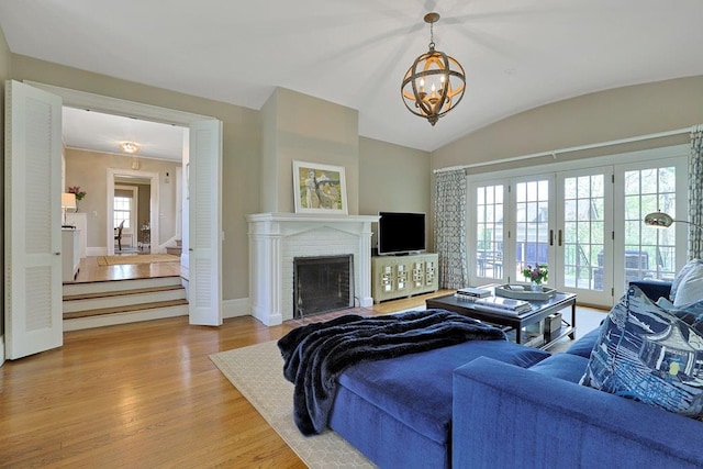 living room with an inviting chandelier, plenty of natural light, french doors, and light wood-type flooring