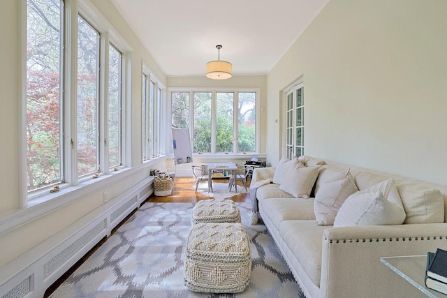sunroom / solarium with a baseboard heating unit, wood finished floors, and a wealth of natural light