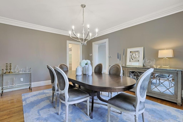 dining area featuring an inviting chandelier, crown molding, and wood finished floors