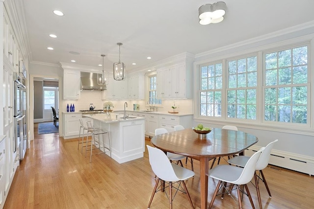 dining space with recessed lighting, ornamental molding, and light wood-type flooring