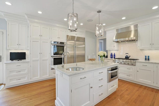 kitchen featuring crown molding, wall chimney range hood, white cabinetry, light wood-style flooring, and appliances with stainless steel finishes