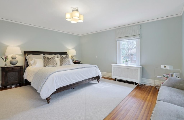 bedroom with baseboards, radiator heating unit, and wood finished floors