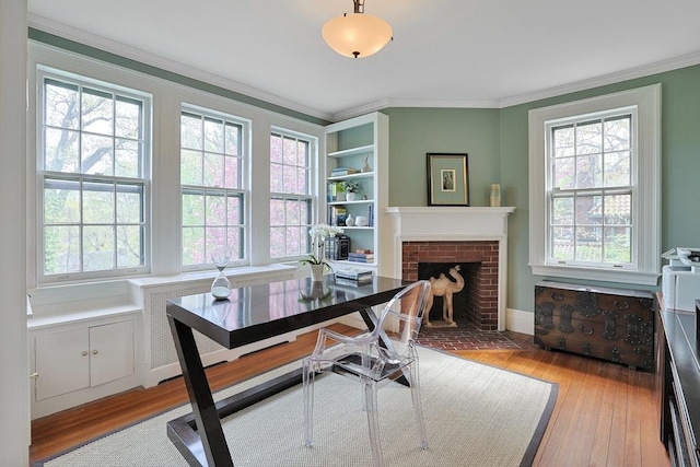 home office featuring baseboards, ornamental molding, light wood finished floors, and a fireplace