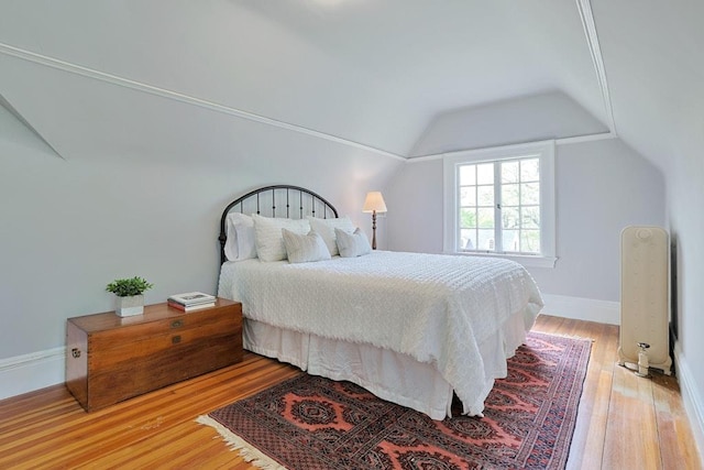 bedroom featuring baseboards, light wood-style flooring, and lofted ceiling