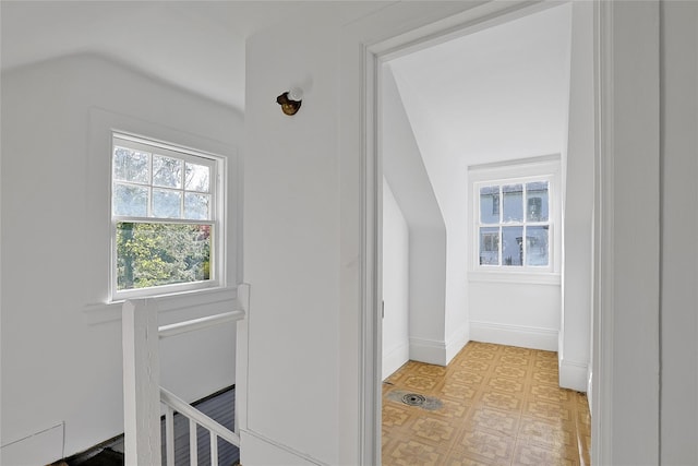 hallway with baseboards, an upstairs landing, and lofted ceiling