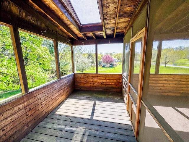 unfurnished sunroom with a skylight, wooden walls, and hardwood / wood-style floors