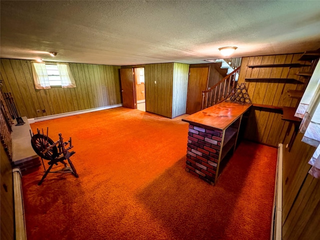 interior space featuring carpet floors, wood walls, stairs, and a textured ceiling