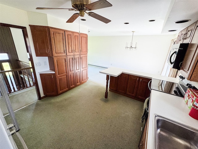 kitchen with light countertops, ceiling fan with notable chandelier, recessed lighting, a peninsula, and pendant lighting