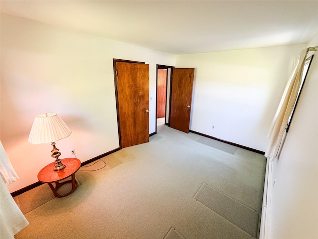 unfurnished bedroom featuring baseboards and light colored carpet