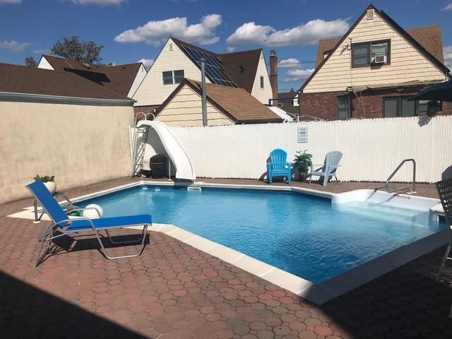 158-35 91st St, Howard Beach, NY 11414 - view of swimming pool with a fenced in pool, a fenced backyard, a patio area, and a water slide