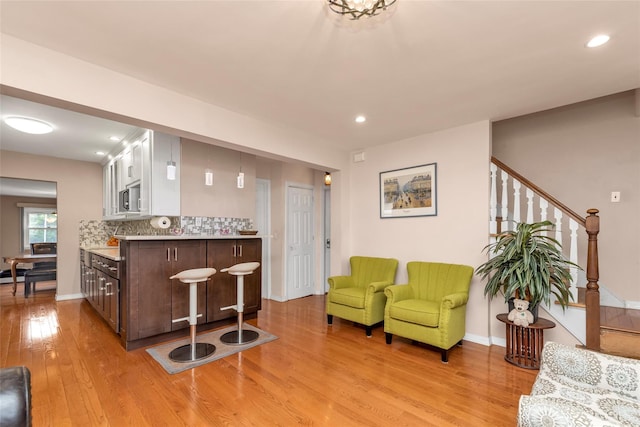 102 Spruce Ln, Valley Stream, NY 11581 - bar with stainless steel microwave, light wood-style floors, tasteful backsplash, recessed lighting, and stairs