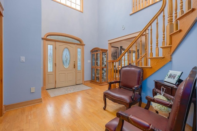 entryway with stairway, baseboards, a high ceiling, and wood finished floors