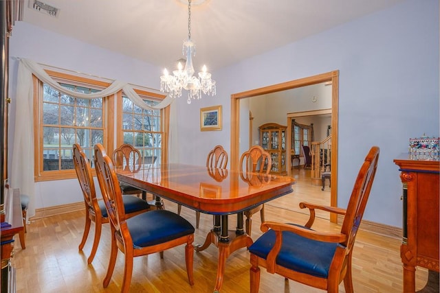 dining room featuring light wood-style floors, baseboards, a notable chandelier, and visible vents
