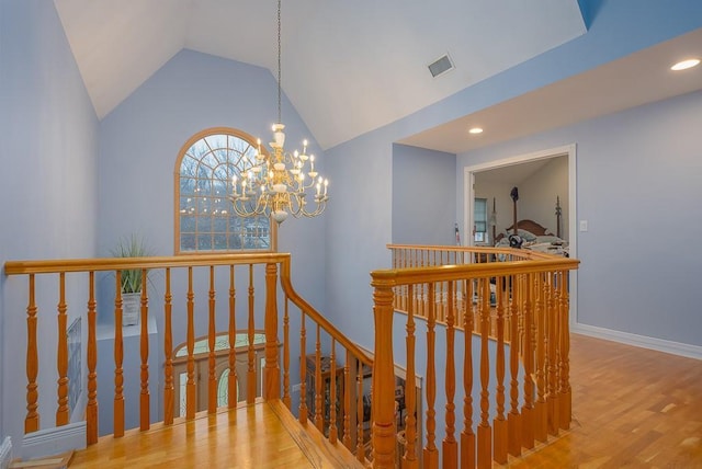 staircase with visible vents, vaulted ceiling, wood finished floors, an inviting chandelier, and recessed lighting