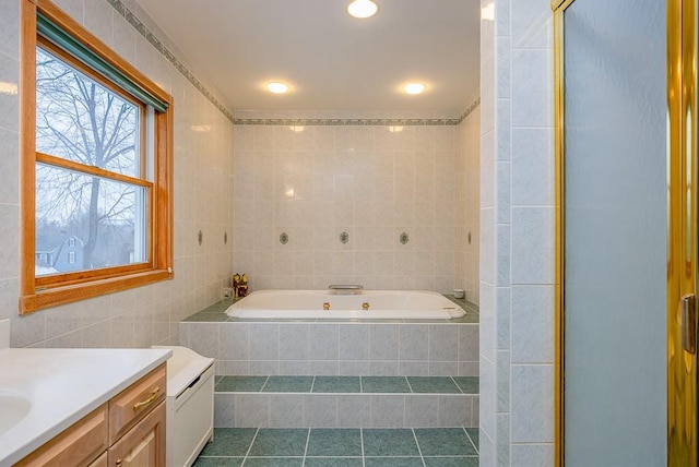 bathroom with a bath, tile walls, tile patterned flooring, a shower stall, and vanity