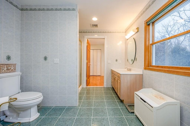 bathroom featuring visible vents, vanity, tile walls, tile patterned floors, and a stall shower