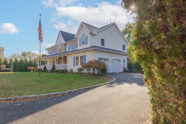 view of front facade featuring covered porch, an attached garage, driveway, and a front yard