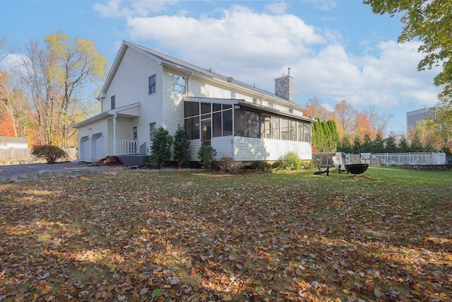 view of property exterior featuring a sunroom, a garage, and a chimney