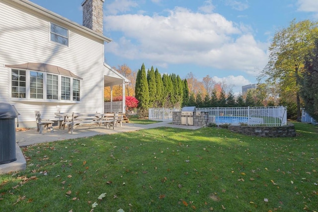 view of yard featuring fence, a patio, an outdoor kitchen, a swimming pool, and central air condition unit