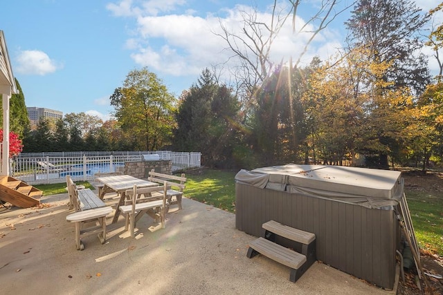 view of patio with fence, outdoor dining area, and a hot tub