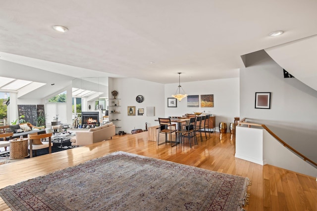 dining space with recessed lighting, a warm lit fireplace, and hardwood / wood-style flooring