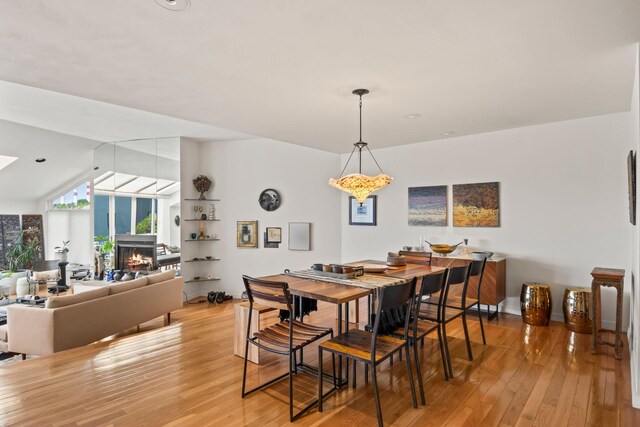 dining space with light wood-style floors and a lit fireplace