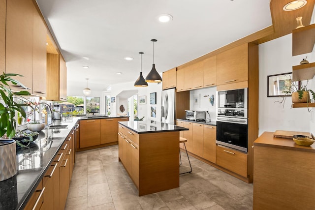 kitchen featuring a sink, stainless steel appliances, recessed lighting, a peninsula, and pendant lighting