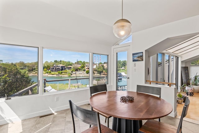 dining space with a water view, light tile patterned flooring, and lofted ceiling
