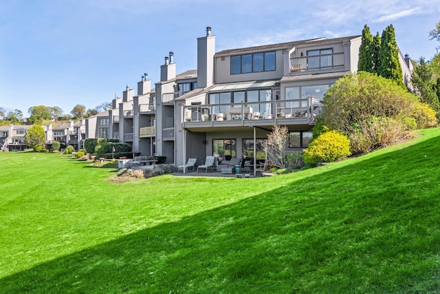 rear view of property with a lawn, a patio, a residential view, and a balcony