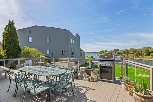 wooden terrace featuring a water view, a yard, area for grilling, and outdoor dining space