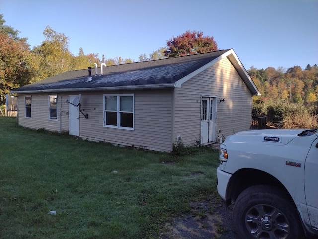 back of property featuring a lawn and a shingled roof