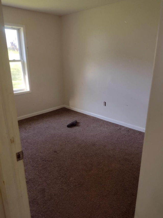 spare room with dark carpet and baseboards