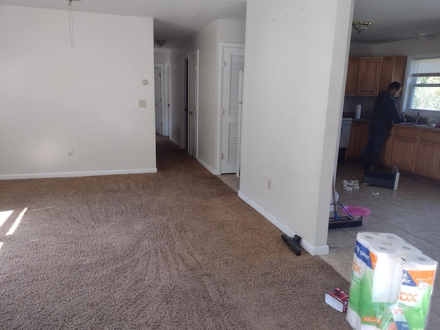empty room with a sink, light carpet, and baseboards