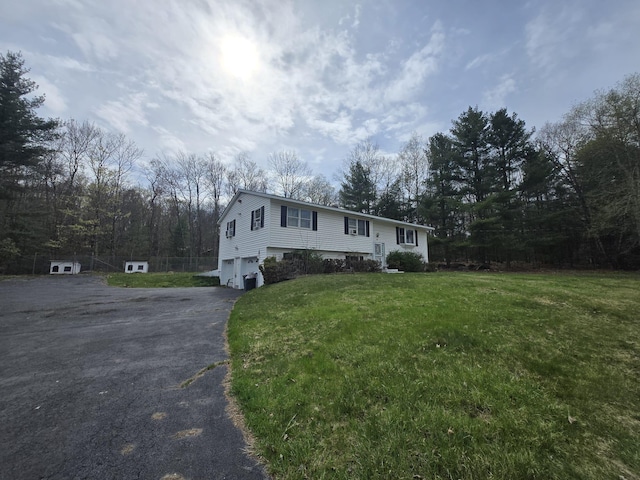 bi-level home with a front yard, a garage, and aphalt driveway
