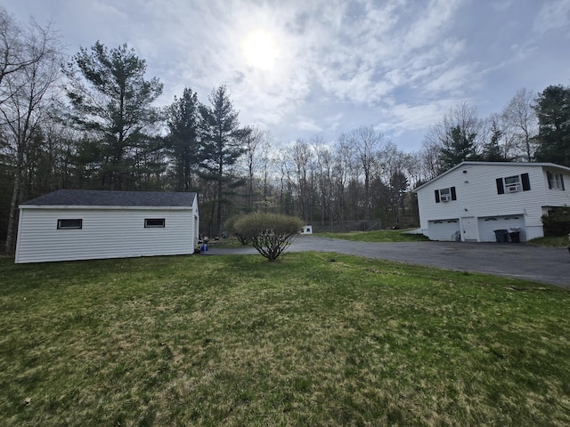 view of yard with an outdoor structure, a garage, and aphalt driveway