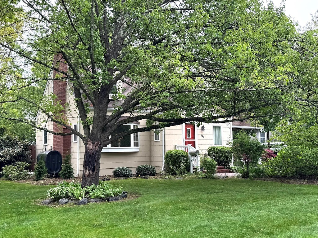 541 Peters Blvd, Brightwaters, NY 11718 - view of front of house featuring a front lawn, a chimney, and heating fuel