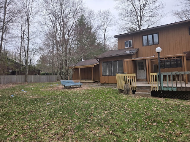 rear view of property featuring a lawn, a wooden deck, and fence